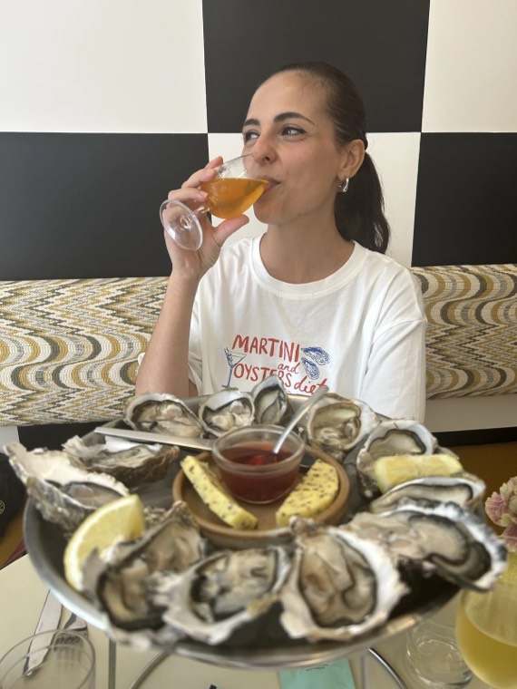 A guest sipping a drink with a platter of oysters and lemon