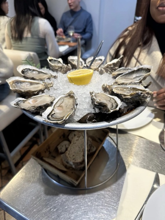 A tiered platter of fresh oysters on ice with lemon