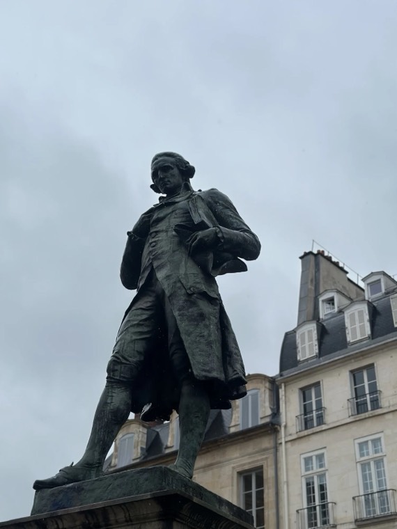 A bronze statue against the sky with Paris rooftops behind