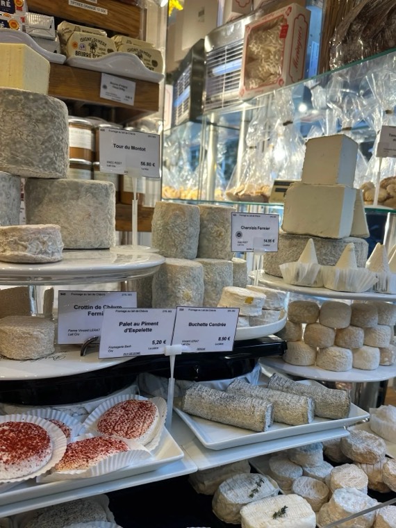 A cheese counter with rounds of cheese and sliced charcuterie