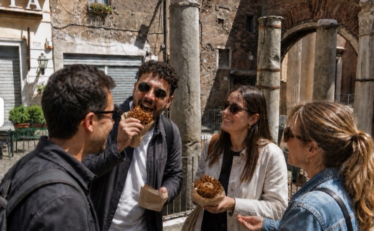 Guests sharing snacks among ancient columns in Rome