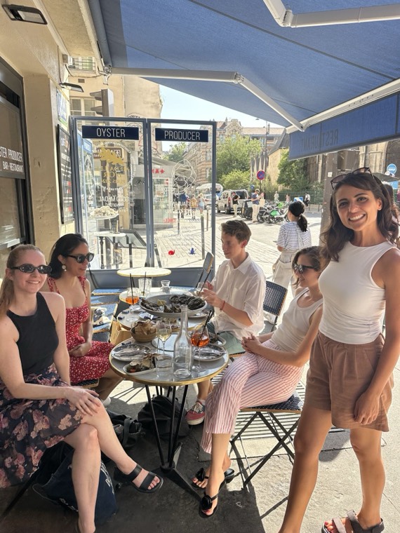Guests seated at a table under a blue awning outside an oyster bar in Paris