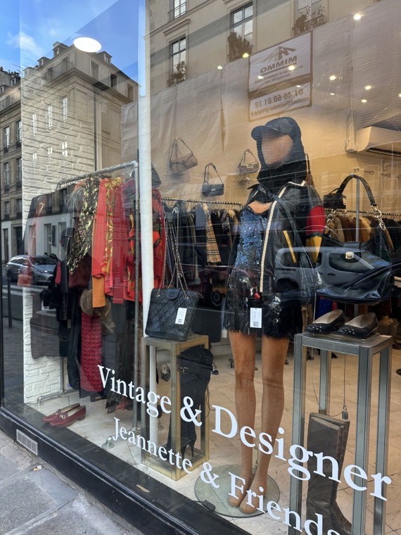 A shop window with designer handbags and a sequinned outfit on a mannequin, with the words Vintage & Designer